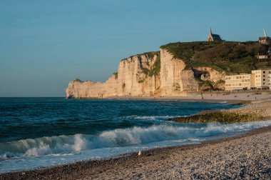 Etretat 'ın ikonik tebeşir kayalıkları ve turkuaz suları güneş ışığı altında parlayarak Normandiya' nın doğal güzelliğini ve huzurlu sahil şeridini gözler önüne seriyor..