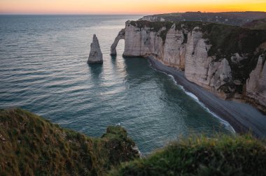 Etretat 'ın ikonik tebeşir kayalıkları ve turkuaz suları güneş ışığı altında parlayarak Normandiya' nın doğal güzelliğini ve huzurlu sahil şeridini gözler önüne seriyor..