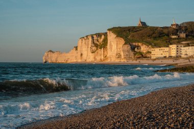 Etretat 'ın ikonik tebeşir kayalıkları ve turkuaz suları güneş ışığı altında parlayarak Normandiya' nın doğal güzelliğini ve huzurlu sahil şeridini gözler önüne seriyor..