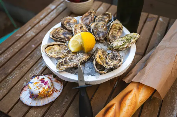 Limon, kabuklu baget, kremalı tereyağı ve bir bardak geleneksel Fransız şarabı ile servis edilen lezzetli çiğ istiridye tabağı..