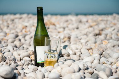 Şişesinin yanındaki bir bardakta serinletici Fransız şarabı arka planda kıyı kayalıkları olan Etretat 'ın çakıllı kıyısında dinleniyor..