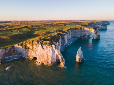 Etretat 'ın ikonik tebeşir kayalıkları ve turkuaz suları güneş ışığı altında parlayarak Normandiya' nın doğal güzelliğini ve huzurlu sahil şeridini gözler önüne seriyor..