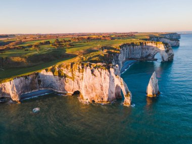 Etretat 'ın ikonik tebeşir kayalıkları ve turkuaz suları güneş ışığı altında parlayarak Normandiya' nın doğal güzelliğini ve huzurlu sahil şeridini gözler önüne seriyor..