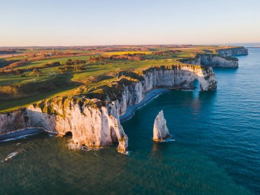 Etretat 'ın ikonik tebeşir kayalıkları ve turkuaz suları güneş ışığı altında parlayarak Normandiya' nın doğal güzelliğini ve huzurlu sahil şeridini gözler önüne seriyor..