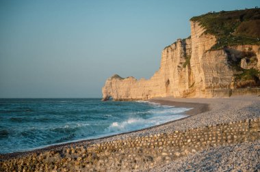 Etretat 'ın ikonik tebeşir kayalıkları ve turkuaz suları güneş ışığı altında parlayarak Normandiya' nın doğal güzelliğini ve huzurlu sahil şeridini gözler önüne seriyor..