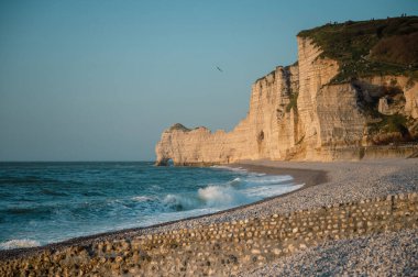 Etretat 'ın ikonik tebeşir kayalıkları ve turkuaz suları güneş ışığı altında parlayarak Normandiya' nın doğal güzelliğini ve huzurlu sahil şeridini gözler önüne seriyor..
