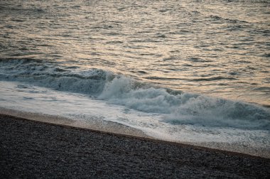 Etretat, Normandiya 'nın ikonik beyaz uçurumlarının yakınındaki turkuaz sulara güçlü bir dalga çarpar ve denizin saf güzelliğini gösterir..