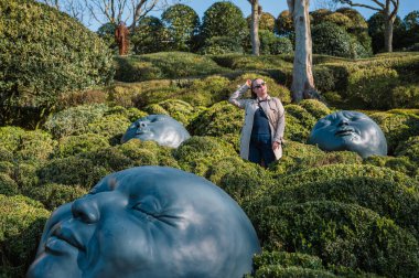 Jardins dEtretat 'ın sanatsal manzaralarında gezinen bir kadın, yontulmuş yeşillik ve Alabaster Sahili' nin panoramik manzaralarıyla çevrili..