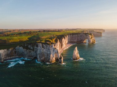 Etretat 'ın ikonik tebeşir kayalıkları ve turkuaz suları güneş ışığı altında parlayarak Normandiya' nın doğal güzelliğini ve huzurlu sahil şeridini gözler önüne seriyor..