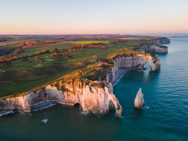 Etretat 'ın ikonik tebeşir kayalıkları ve turkuaz suları güneş ışığı altında parlayarak Normandiya' nın doğal güzelliğini ve huzurlu sahil şeridini gözler önüne seriyor..