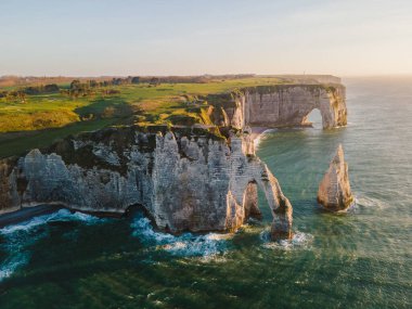 Etretat 'ın ikonik tebeşir kayalıkları ve turkuaz suları güneş ışığı altında parlayarak Normandiya' nın doğal güzelliğini ve huzurlu sahil şeridini gözler önüne seriyor..