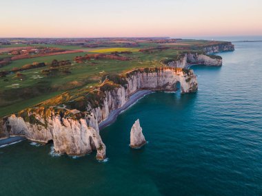 Etretat 'ın ikonik tebeşir kayalıkları ve turkuaz suları güneş ışığı altında parlayarak Normandiya' nın doğal güzelliğini ve huzurlu sahil şeridini gözler önüne seriyor..