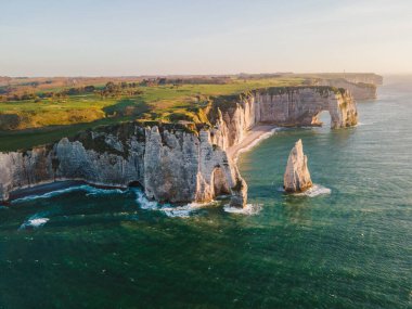 Etretat 'ın ikonik tebeşir kayalıkları ve turkuaz suları güneş ışığı altında parlayarak Normandiya' nın doğal güzelliğini ve huzurlu sahil şeridini gözler önüne seriyor..