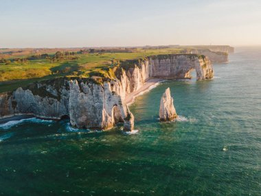 Etretat 'ın ikonik tebeşir kayalıkları ve turkuaz suları güneş ışığı altında parlayarak Normandiya' nın doğal güzelliğini ve huzurlu sahil şeridini gözler önüne seriyor..