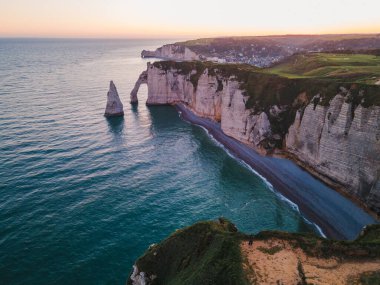 Etretat 'ın ikonik tebeşir kayalıkları ve turkuaz suları güneş ışığı altında parlayarak Normandiya' nın doğal güzelliğini ve huzurlu sahil şeridini gözler önüne seriyor..