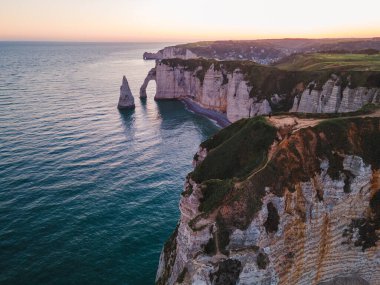Etretat 'ın ikonik tebeşir kayalıkları ve turkuaz suları güneş ışığı altında parlayarak Normandiya' nın doğal güzelliğini ve huzurlu sahil şeridini gözler önüne seriyor..