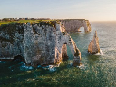 Etretat 'ın ikonik tebeşir kayalıkları ve turkuaz suları güneş ışığı altında parlayarak Normandiya' nın doğal güzelliğini ve huzurlu sahil şeridini gözler önüne seriyor..