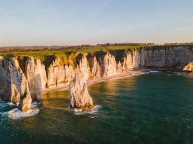 Etretat 'ın ikonik tebeşir kayalıkları ve turkuaz suları güneş ışığı altında parlayarak Normandiya' nın doğal güzelliğini ve huzurlu sahil şeridini gözler önüne seriyor..