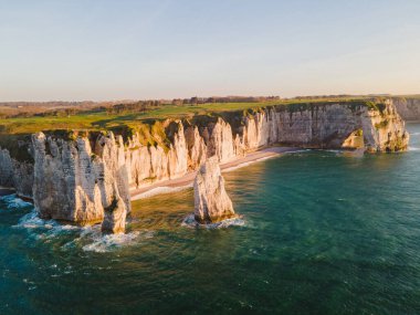 Etretat 'ın ikonik tebeşir kayalıkları ve turkuaz suları güneş ışığı altında parlayarak Normandiya' nın doğal güzelliğini ve huzurlu sahil şeridini gözler önüne seriyor..