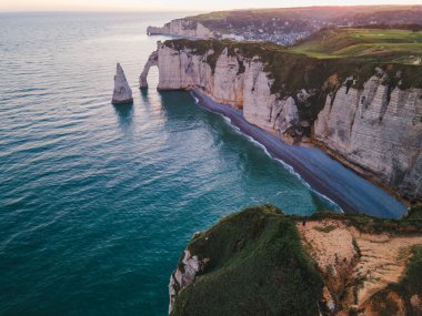 Etretat 'ın ikonik tebeşir kayalıkları ve turkuaz suları güneş ışığı altında parlayarak Normandiya' nın doğal güzelliğini ve huzurlu sahil şeridini gözler önüne seriyor..