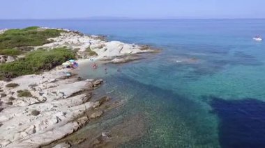 Yunanistan 'ın Chalkidiki kentindeki Karydi Sahili yakınlarındaki Sithonia kıyı şeridinin nefes kesici manzarası. Kristal berraklığında turkuaz sular engebeli kaya oluşumlarıyla birleşerek pitoresk bir Akdeniz cenneti yaratıyor..