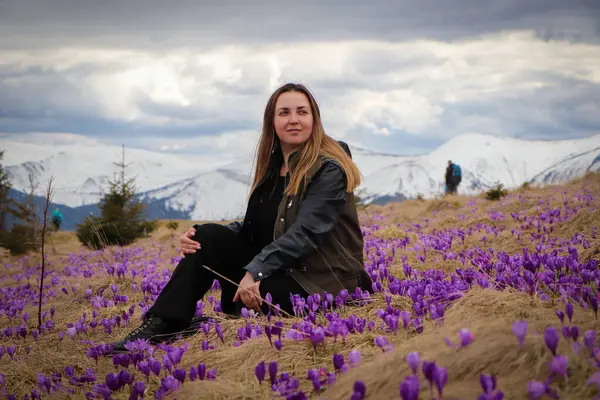 Genç bir kadın, canlı, çiçek açan timsahlarla çevrili Karpat Dağları 'nın nefes kesici güzelliğinin tadını çıkarıyor. Arka plandaki sihirli tepeler çarpıcı bir doğal manzara yaratır..