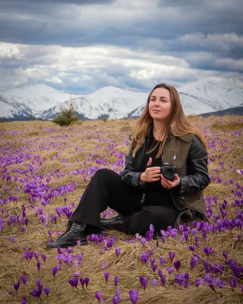 Genç bir kadın, canlı, çiçek açan timsahlarla çevrili Karpat Dağları 'nın nefes kesici güzelliğinin tadını çıkarıyor. Arka plandaki sihirli tepeler çarpıcı bir doğal manzara yaratır..