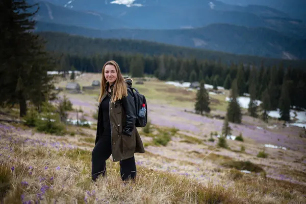 Genç bir kadın, canlı, çiçek açan timsahlarla çevrili Karpat Dağları 'nın nefes kesici güzelliğinin tadını çıkarıyor. Arka plandaki sihirli tepeler çarpıcı bir doğal manzara yaratır..