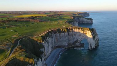 Etretat 'ın ikonik tebeşir kayalıkları ve turkuaz suları güneş ışığı altında parlayarak Normandiya' nın doğal güzelliğini ve huzurlu sahil şeridini gözler önüne seriyor..