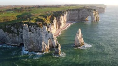 Etretat 'ın ikonik tebeşir kayalıkları ve turkuaz suları güneş ışığı altında parlayarak Normandiya' nın doğal güzelliğini ve huzurlu sahil şeridini gözler önüne seriyor..