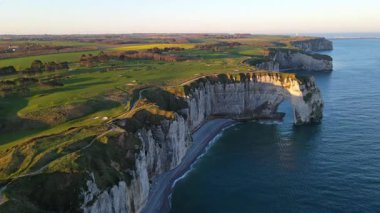 Etretat 'ın ikonik tebeşir kayalıkları ve turkuaz suları güneş ışığı altında parlayarak Normandiya' nın doğal güzelliğini ve huzurlu sahil şeridini gözler önüne seriyor..