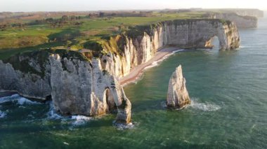 Etretat 'ın ikonik tebeşir kayalıkları ve turkuaz suları güneş ışığı altında parlayarak Normandiya' nın doğal güzelliğini ve huzurlu sahil şeridini gözler önüne seriyor..