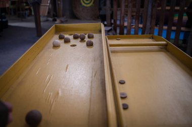Klasik ahşap bir Sjoelbak karıştırma tahtası oyunu rahat bir çiftlik ortamında geleneksel eğlenceyi kırsal cazibeyle harmanlıyor..