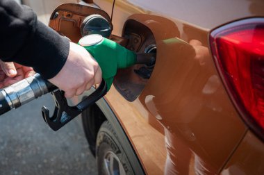 Adam benzin pompasında arabaya benzin dolduruyor. Modern bir benzin istasyonundaki yakıt ikmal işlemini yakından görüyor..