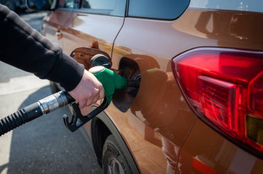 Adam benzin pompasında arabaya benzin dolduruyor. Modern bir benzin istasyonundaki yakıt ikmal işlemini yakından görüyor..