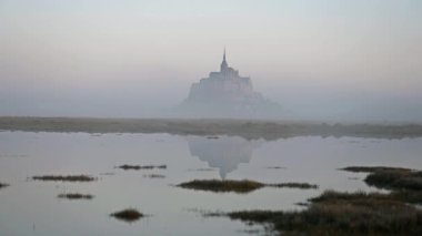İkonik Mont Saint-Michel, kasvetli bir günde, ortaçağ köyü ve Normandiya kıyılarında sisli bir manastır ile yoğun bir siste ortaya çıkar.