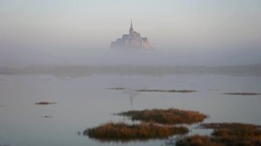 İkonik Mont Saint-Michel, kasvetli bir günde, ortaçağ köyü ve Normandiya kıyılarında sisli bir manastır ile yoğun bir siste ortaya çıkar.