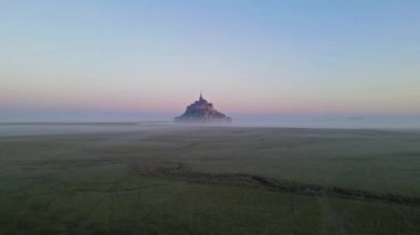 İkonik Mont Saint-Michel, kasvetli bir günde, ortaçağ köyü ve Normandiya kıyılarında sisli bir manastır ile yoğun bir siste ortaya çıkar.