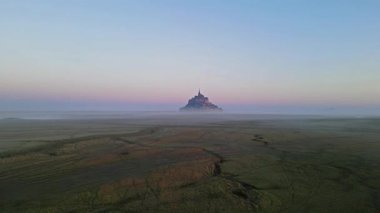 İkonik Mont Saint-Michel, kasvetli bir günde, ortaçağ köyü ve Normandiya kıyılarında sisli bir manastır ile yoğun bir siste ortaya çıkar.