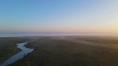 Altın gün doğumu ışığı, Mont Saint-Michel 'i çevreleyen sisli bataklıkları yansıtır. Huzurlu bir sabah atmosferinde manastırı ve köyü aydınlatır..