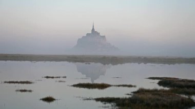 İkonik Mont Saint-Michel, kasvetli bir günde, ortaçağ köyü ve Normandiya kıyılarında sisli bir manastır ile yoğun bir siste ortaya çıkar.