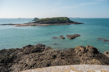 Saint-Malo sahilinin panoramik manzarası, altın kum, nazik dalgalar ve Brittany kıyısı boyunca tarihi cazibe.