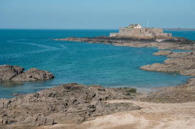 Saint-Malo sahilinin panoramik manzarası, altın kum, nazik dalgalar ve Brittany kıyısı boyunca tarihi cazibe.