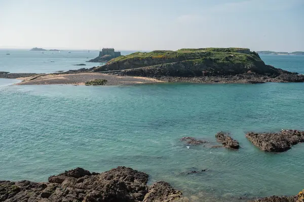 Saint-Malo sahilinin panoramik manzarası, altın kum, nazik dalgalar ve Brittany kıyısı boyunca tarihi cazibe.