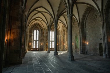 Mont Saint-Michel Manastırı 'nın sakin ve tarihi iç kısımları taş kemerler, antik duvarlar ve dar pencerelerden süzülen yumuşak doğal ışık..