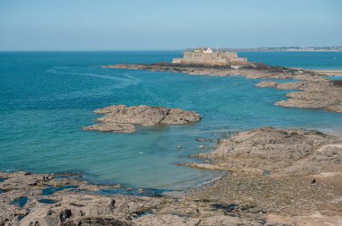 Saint-Malo sahilinin panoramik manzarası, altın kum, nazik dalgalar ve Brittany kıyısı boyunca tarihi cazibe.
