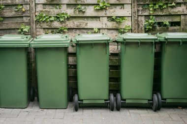 Parlak renkli çöp ve geri dönüşüm kutuları, kentsel alanlarda atık ayrımını ve çevresel sürdürülebilirliği teşvik etmek amacıyla bir şehir caddesinde sıraya dizilmişti..