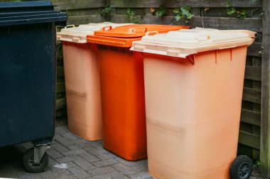 Parlak renkli çöp ve geri dönüşüm kutuları, kentsel alanlarda atık ayrımını ve çevresel sürdürülebilirliği teşvik etmek amacıyla bir şehir caddesinde sıraya dizilmişti..