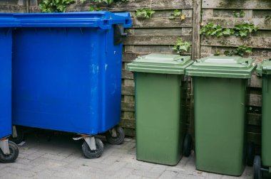 Parlak renkli çöp ve geri dönüşüm kutuları, kentsel alanlarda atık ayrımını ve çevresel sürdürülebilirliği teşvik etmek amacıyla bir şehir caddesinde sıraya dizilmişti..