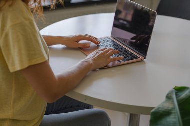 Genç bir kadın ev işlerinin rahatlığıyla uzaktan yakından ilgilenirken bilgisayarına odaklanmış..